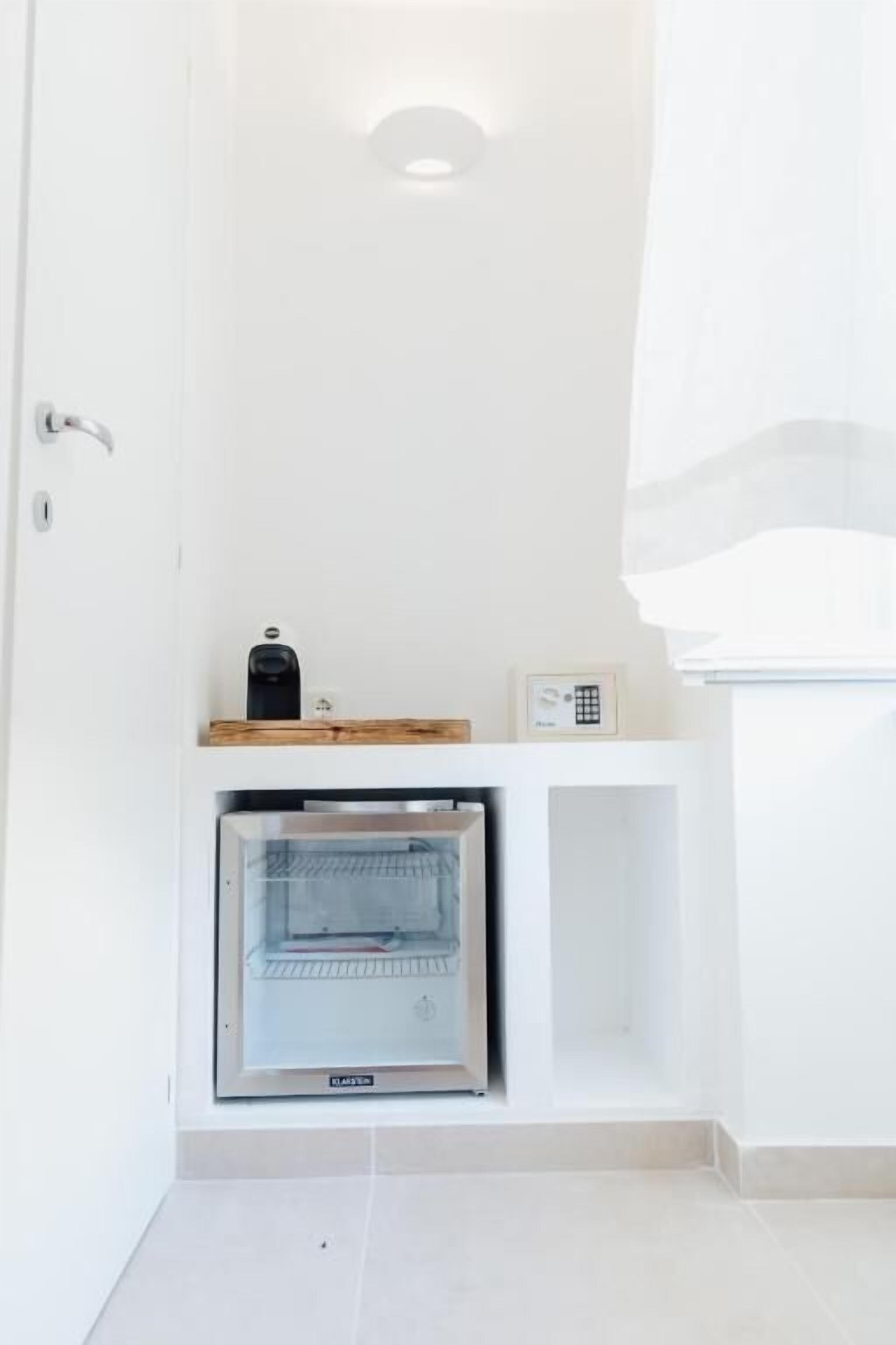 A compact kitchen with a built-in oven, a coffee maker, and a small shelf.