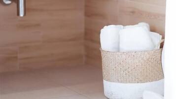 Un baño con lavamanos blanco, baldosas de madera y una cesta de mimbre con toallas.