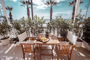 A wooden table and chairs set up on a terrace with potted plants and a view of the sea. - Break For Two (Agropoli)