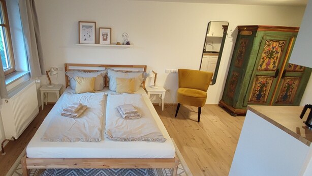 A bedroom with a bed, bedside tables, a chair, a radiator, and a wardrobe. - Appartement am Weißbach - Urlaub im Pfrontener Tal (Pfronten)