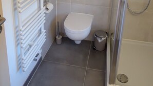 A bathroom with a toilet, a shower, and a radiator. - Appartement am Weißbach - Urlaub im Pfrontener Tal (Pfronten)