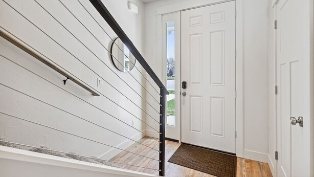 A staircase with white walls and a black handrail leading to a white door with a doormat. - My Glacier Getaway - 3 min to downtown Kalispell! (Kalispell)
