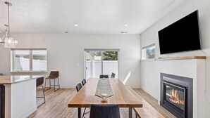 A modern kitchen with a wooden dining table, a built-in island, and a fireplace. - My Glacier Getaway - 3 min to downtown Kalispell! (Kalispell)