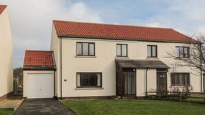 A two-story house with a red-tiled roof, a garage, and a front door. - Causeway Cottage (Berwick-upon-Tweed)