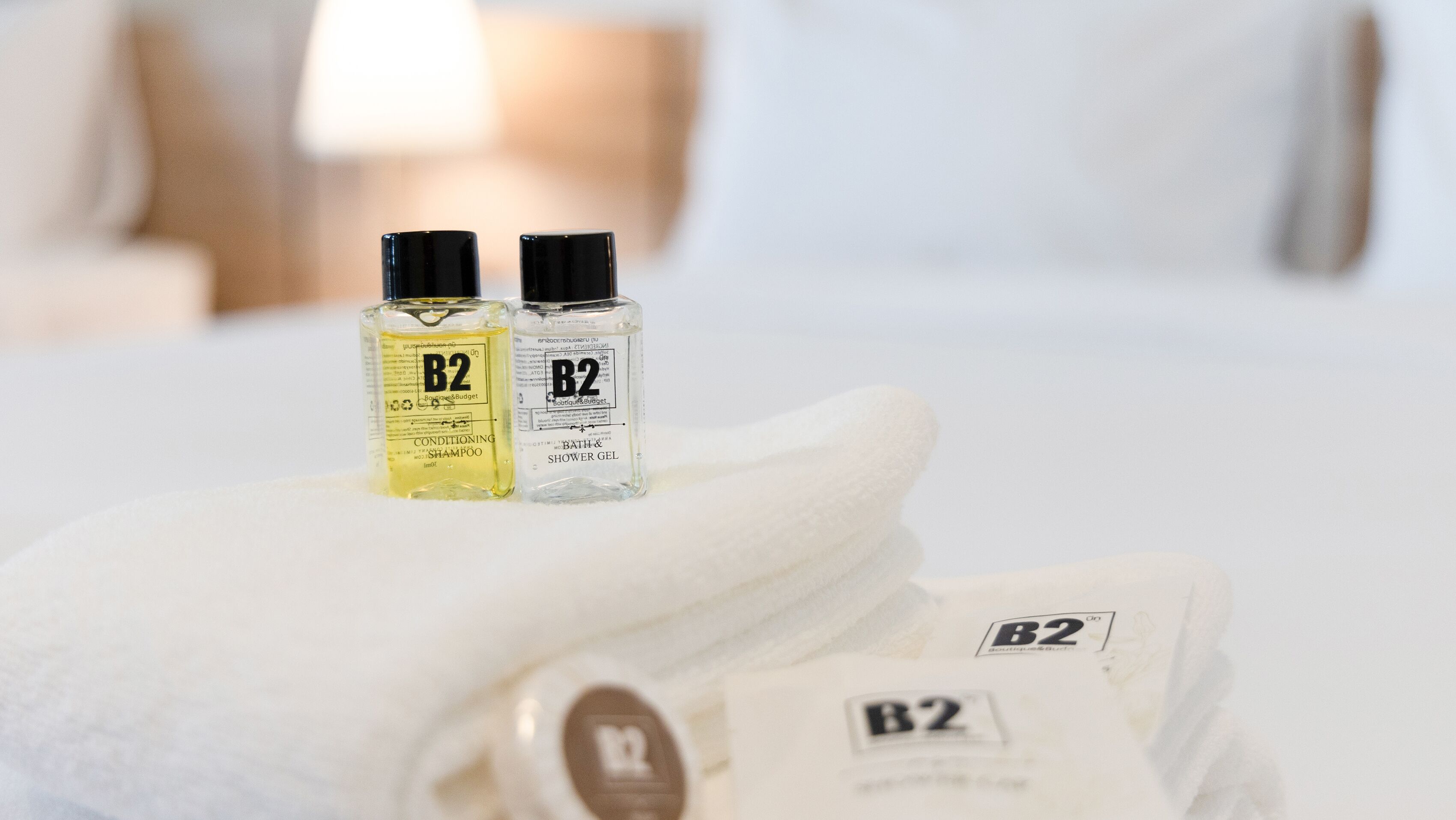 Twee flessen B2 conditionerende shampoo en B2 bad- en douchegel op een witte handdoek.