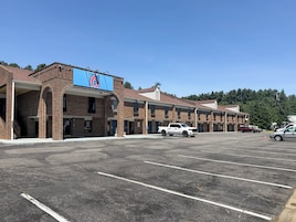 Un motel con varias habitaciones, un estacionamiento y un cielo azul despejado.