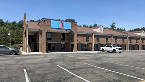 A motel with a large sign, multiple parking spaces, and a brick facade. - Motel 6 Fancy Gap, VA (Fancy Gap)