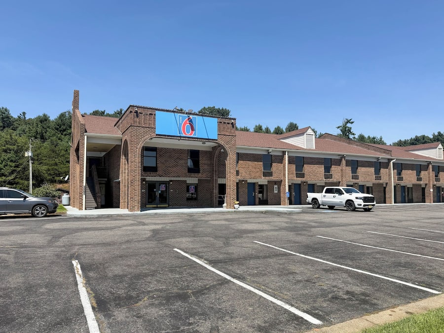 A motel with a large sign, multiple parking spaces, and a brick facade.