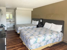 Una habitación de hotel con dos camas, un escritorio y un baño.