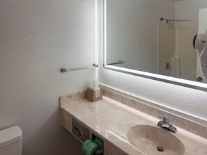 A bathroom with a marble sink, a mirror, a towel dispenser, and a toilet. - Motel 6 Fancy Gap, VA (Fancy Gap)
