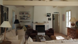 A spacious living room with high ceilings, a fireplace, a bookshelf, and comfortable seating. - Charming house close to the beach, (L'Île-d'Yeu)
