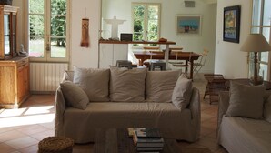 A cozy living room with a sofa, a coffee table, and a dining area with a table and chairs. - Charming house close to the beach, (L'Île-d'Yeu)