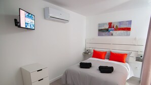 A modern bedroom with a bed, a flat-screen TV, an air conditioner, and a painting on the wall. - BUNGALOW CAMPO DE GOLF (San Bartolomé de Tirajana)