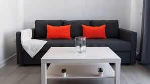 A modern living room with a grey sofa, two red cushions, a white coffee table, and a small plant on the table. - BUNGALOW CAMPO DE GOLF (San Bartolomé de Tirajana)