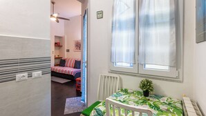 Ein gemütlicher Raum mit einem Bett, einem Tisch mit Pflanze und einem fenster mit Vorhängen.