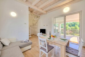 Un salon moderne comprenant un canapé, une table à manger, des chaises, un escalier et un balcon avec vue.