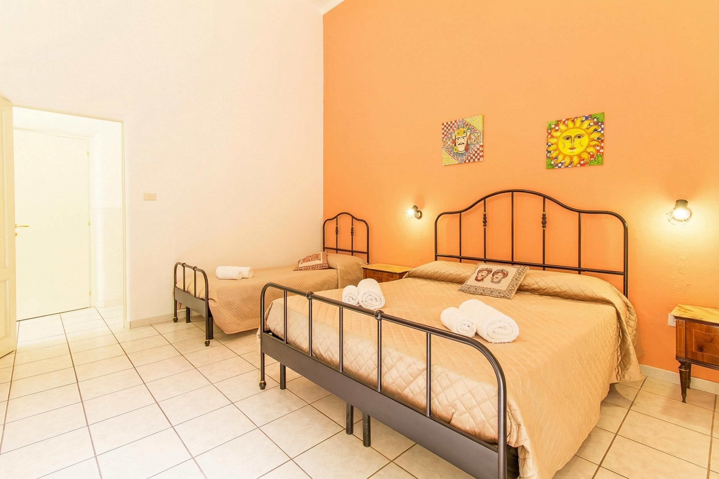 A hotel room with two beds, a door, and a tiled floor.