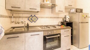 A modern kitchen with a gas stove, oven, microwave, and stainless steel refrigerator. - Sicula home in the city center (Catania)
