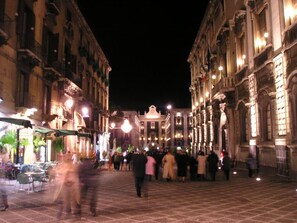 A historic square with ornate buildings, a central fountain, and people walking. - Sicula home in the city center (Catania)