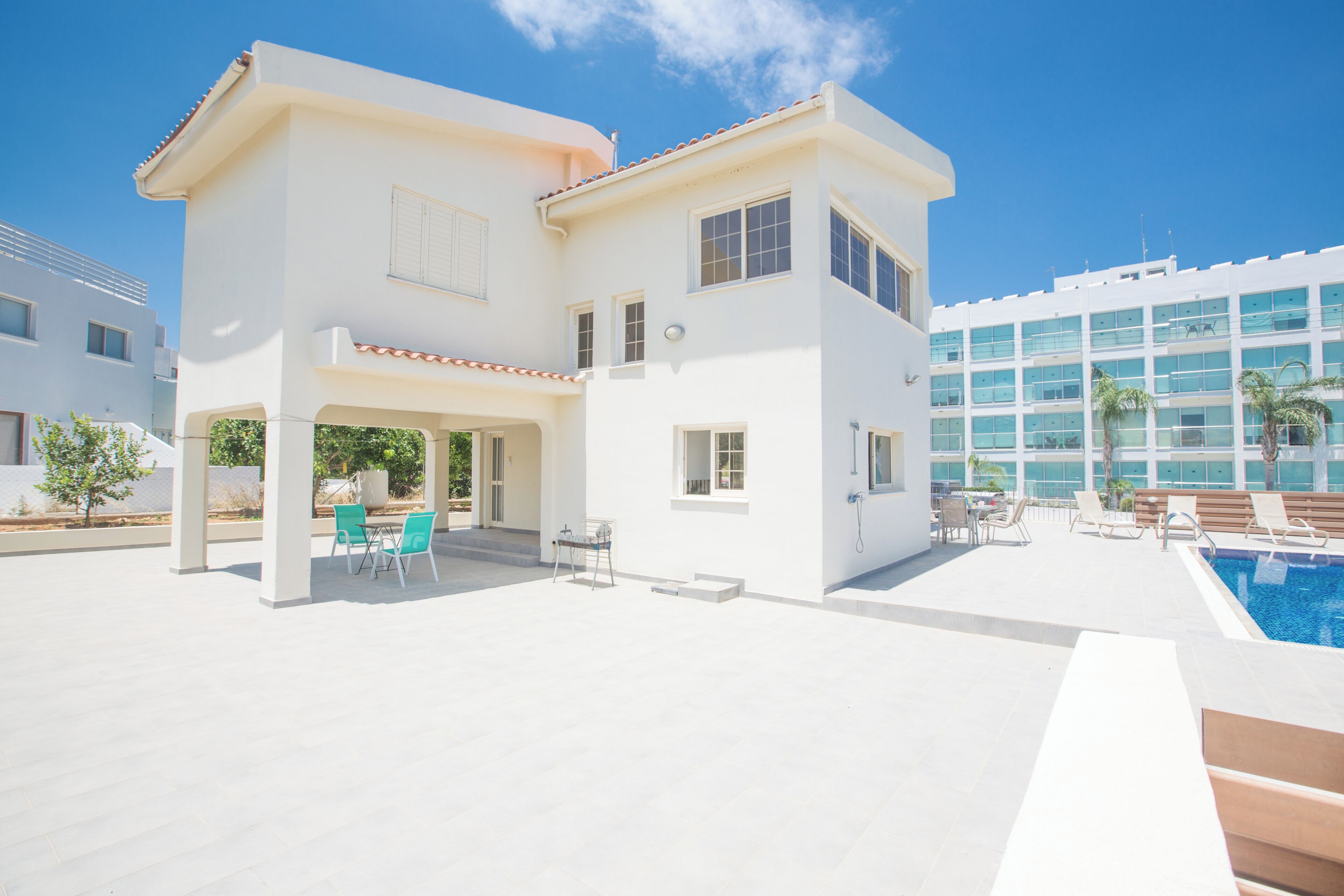 Une maison moderne à deux étages, dotée d’une piscine, d’un espace salon extérieur et d’un patio couvert.