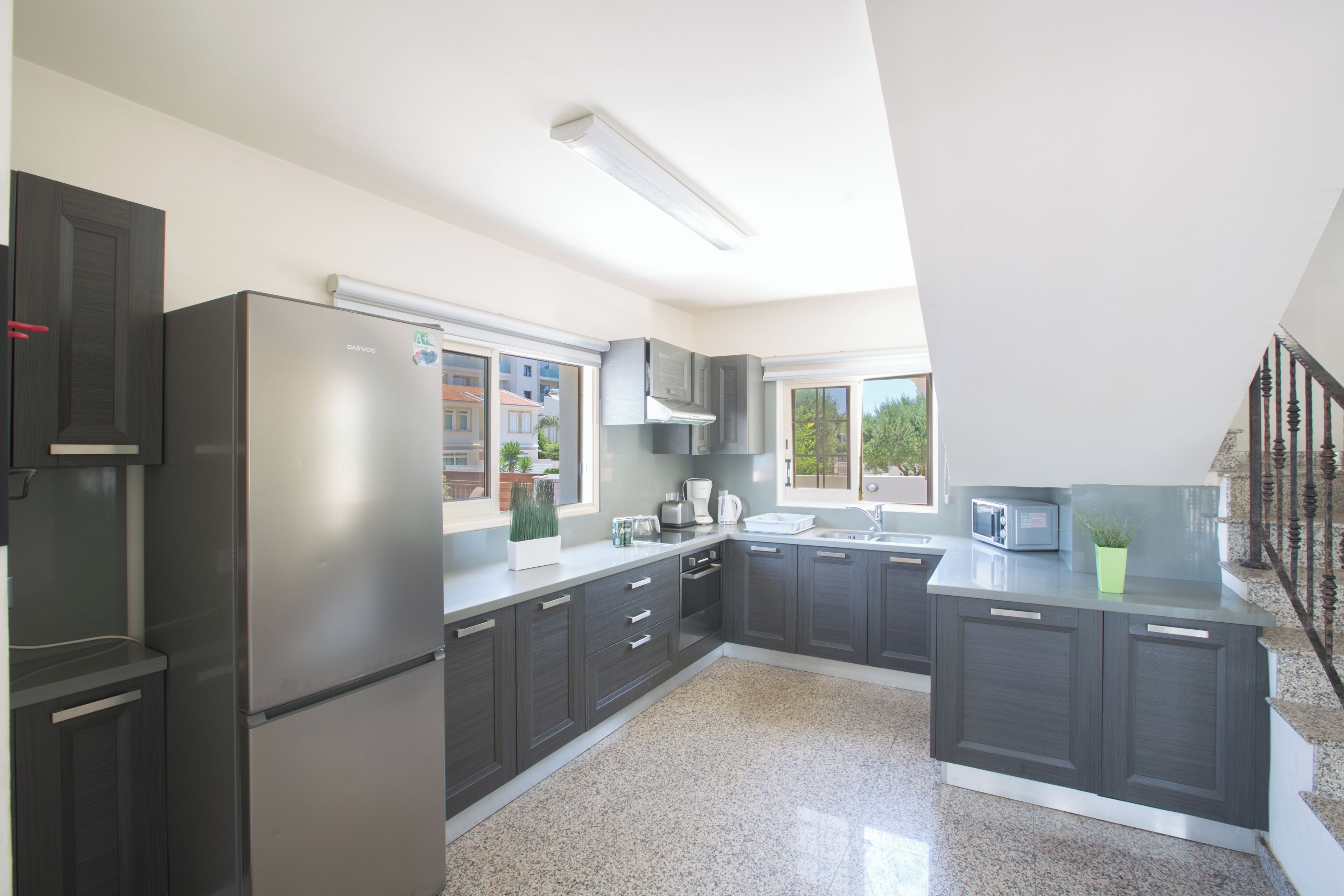 A modern kitchen with dark cabinets, stainless steel appliances, and a granite countertop.