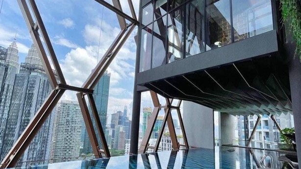 Un edificio moderno con facciata in vetro e piscina sul tetto.