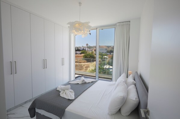 Une chambre à coucher avec un lit, une armoire blanche et une vue sur l’extérieur.
