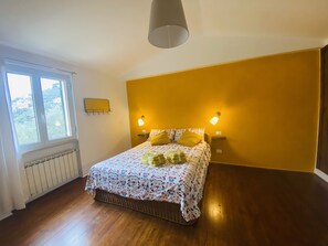 Une chambre à coucher avec un lit, deux lampes de chevet, une fenêtre et un radiateur.