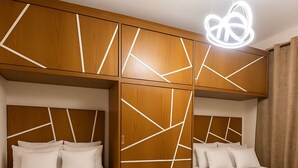 A hotel room with two beds, a wooden wardrobe with geometric patterns, and a modern light fixture. - Luxurious Chalet With Pool View in Porto Said Resor (Al-Manasrah)