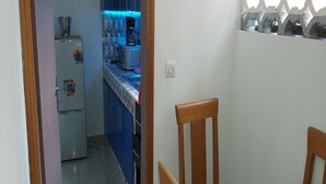 A narrow hallway leading to a kitchen with a refrigerator, microwave, and coffee maker. - Magnifique Studio Meuble (Abidjan)