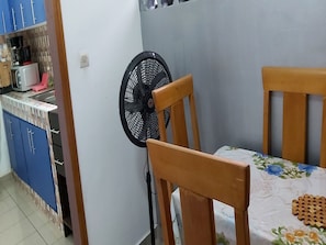 A dining area with a table, chairs, and a wall-mounted fan.
