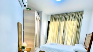 Una camera d'albergo moderna con un letto grande, un armadio, un comodino con una lampada e una finestra con tende.
