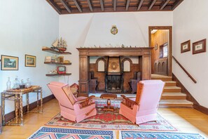 Un salón tradicional con chimenea, muebles de madera y una escalera.