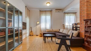 A living room with a sofa, a coffee table, a bookshelf, and a guitar. - 3-bedroom Holiday House Giovanni (Preko)