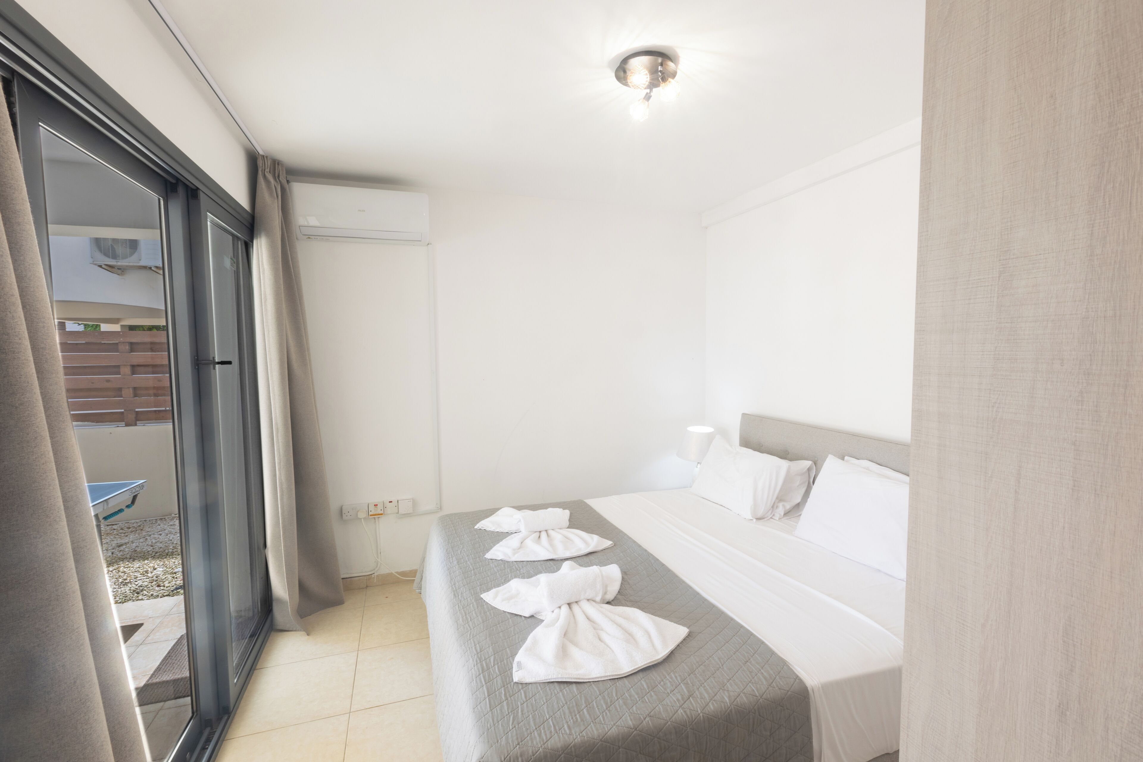 A hotel room with a bed, a window, and a door.