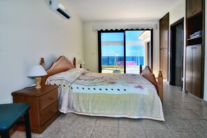 A bedroom with a bed, a nightstand, a chair, a window with a view, and a wardrobe. - Villa Only 50m To The Sea, Sleeps 12, Polis (Pomos)