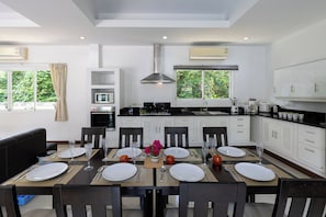 A modern kitchen with white cabinets, a central island, and a dining area set for four.