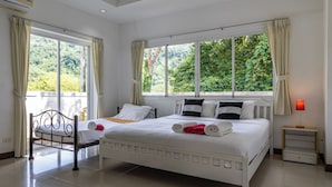 A bedroom with a large bed, a bedside table, a window with curtains, and a view of greenery outside. - Phikun Private Pool Villa (Chalong)
