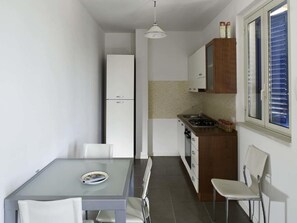 Uma cozinha compacta com mesa e cadeiras, geladeira, fogão e armários.