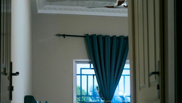 Un dormitorio con cama, mesita de noche y ventana con cortinas.