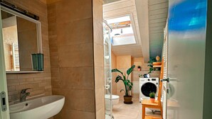 Ein modernes Badezimmer mit großem Waschbecken, Spiegel und Duschbereich.