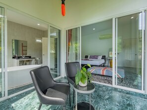 A modern bedroom with a bed, a bathroom with a sink, and a seating area with a plant. - Luxurious 10-bedroom Villa With Private Pool in Chalong, Phuket (Chalong)