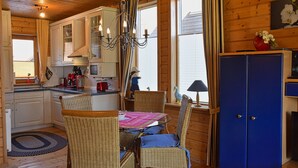Une cuisine chaleureuse, aménagée dans le style d’un chalet, avec des chaises en osier, une table à manger et un buffet bleu.
