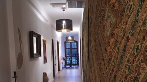 A hallway with a patterned carpet, a ceiling fan, and a large window at the end. - Room in B&B - "note di Stelle" Resort in Marrubiu (Marrubiu)