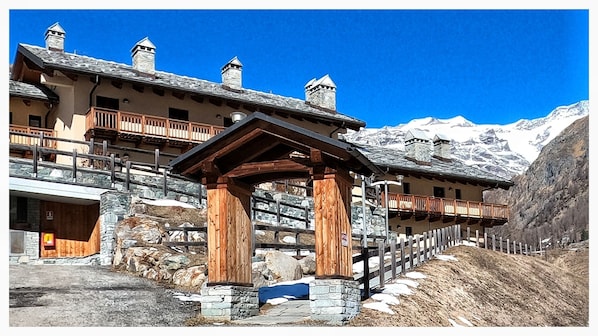 A traditional mountain lodge with stone walls, wooden balconies, and a stone entrance.