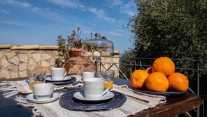 A breakfast setup with cups, a jug, and oranges on a table.