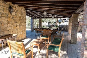 An outdoor patio with stone walls, wooden furniture, and a table with chairs. - Villa Cefalù Private Pool (Cefalù)