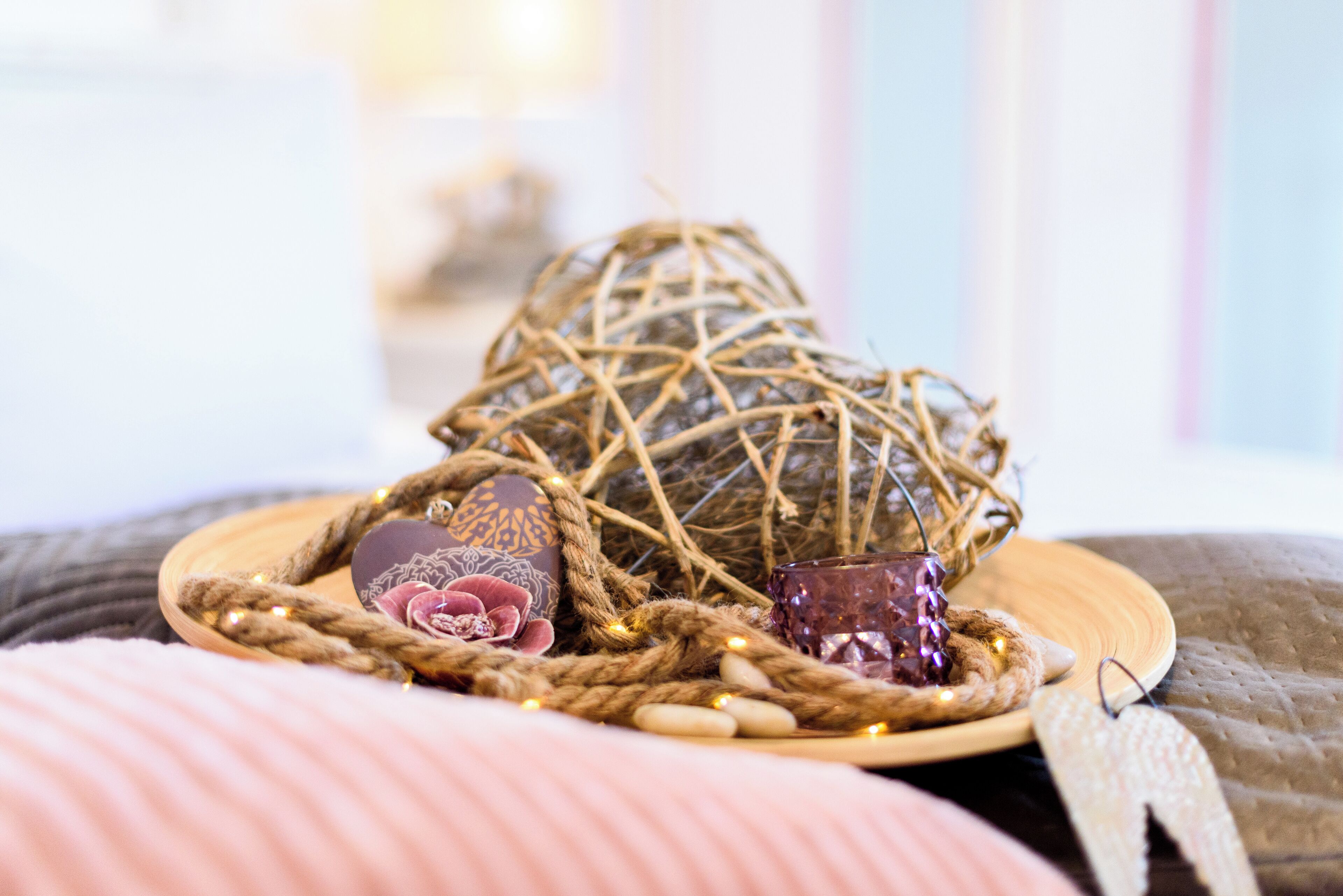 A decorative arrangement with a woven basket, a wooden tray, and various items including a candle and a small decorative object.