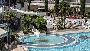 A pool area with a water slide, lounge chairs, and a restaurant. - Super Villaggio Planetarium Resort 1 Bedroom Apartment Sleeps 4 (San Michele al Tagliamento)