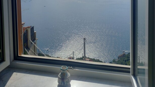 A room with a large window overlooking a coastal view. - Ravello for You Casa Gallo (Ravello)